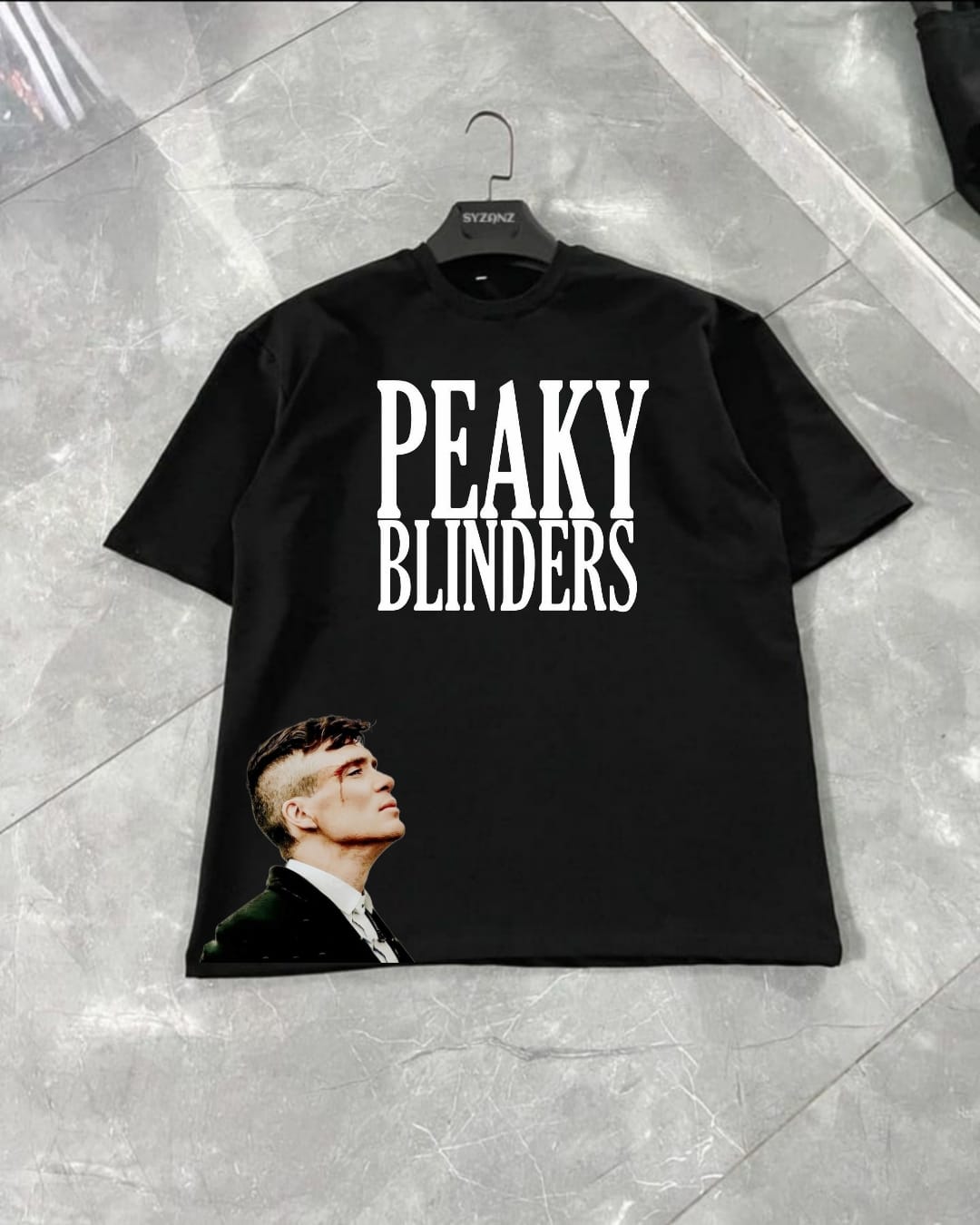 Graphic T-shirt inspired by the iconic 'Peaky Blinders' series, featuring bold and vintage-inspired typography or imagery related to the show's gritty, 1920s Birmingham setting. The design often includes symbols like flat caps, sharp suits, and the Peaky Blinders logo, capturing the essence of the show’s rebellious and stylish characters. Made from soft, high-quality fabric, this T-shirt combines comfort with a nod to the timeless appeal of the gangsters' fashion and attitude, perfect for fans of the series