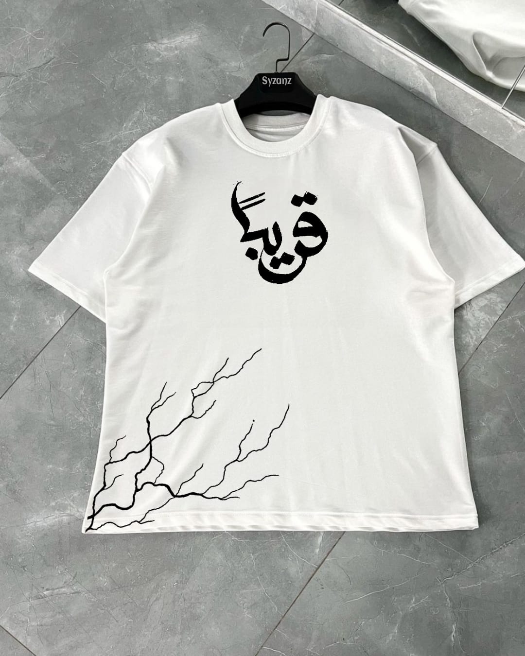 Graphic T-shirt featuring the 'Qareeban' design, which may include bold typography or symbolic elements reflecting themes of closeness, connection, or cultural significance. The design is simple yet striking, making a statement with its clean lines and meaningful message. Made from soft, comfortable fabric, this T-shirt is perfect for those who appreciate minimalist yet impactful fashion, ideal for everyday wear or adding a unique touch to casual outfits.